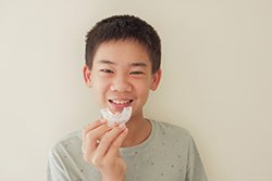 teen smiling and holding a mouthguard