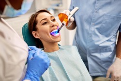 patient with a curing light in her mouth for fillings